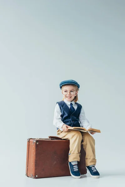 Bambino Sorridente Gilet Retrò Cappuccio Seduto Sulla Valigia Tenendo Libro — Foto Stock