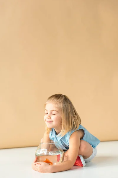 Cute Kid Sitting Crossed Legs Holding Fishbowl Beige Background — Stock Photo, Image