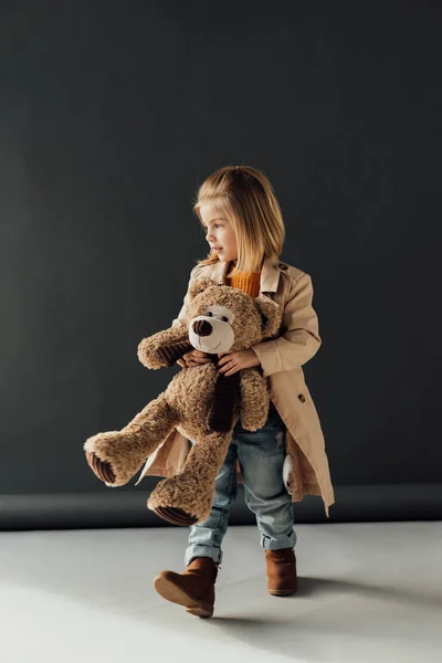 Lindo Niño Gabardina Jeans Sosteniendo Osito Peluche Sobre Fondo Negro — Foto de Stock