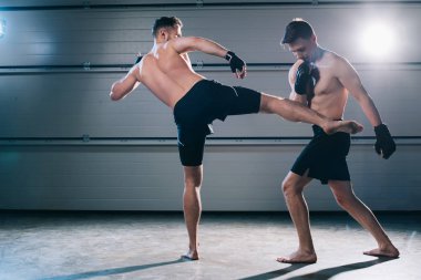 Arkadan görünüş yalınayak mma savaşçı tekme rakibin bacak ile