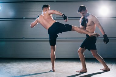 back view of barefoot mma fighter kicking opponent with leg clipart