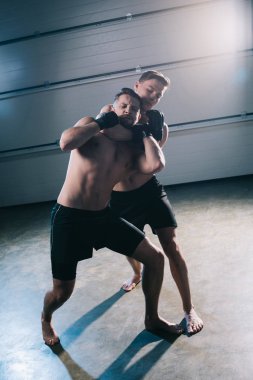 barefoot muscular mma fighter doing chokehold to sportive shirtless opponent  clipart