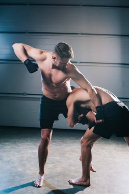 strong muscular shirtless mma fighter punching another while sportsman doing clinch clipart
