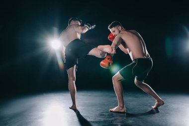 strong mma fighter kicking another sportsman with leg in arm clipart