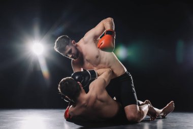 gömleksiz güçlü mma savaşçı rakip yerde yatarken sporcu ise kafasına yumruk boks eldiven