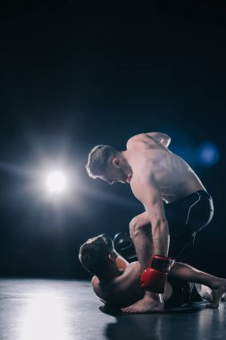 gömleksiz güçlü mma savaşçı boks rakip üzerinde duran ve onu yerde yatarken sporcu ise kafasına yumruk eldiven