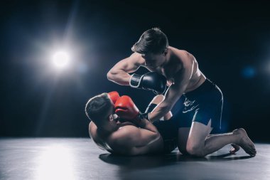 gömleksiz güçlü mma savaşçı boks rakip yukarıda dizlerinin üzerinde duran ve onu dirsek ile Delme eldiven