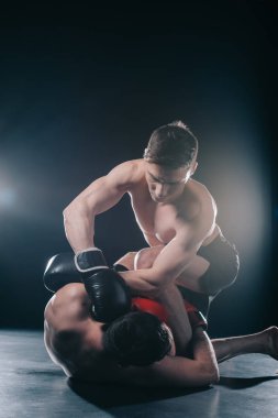 shirtless strong mma fighter in boxing gloves clinching opponent on floor clipart