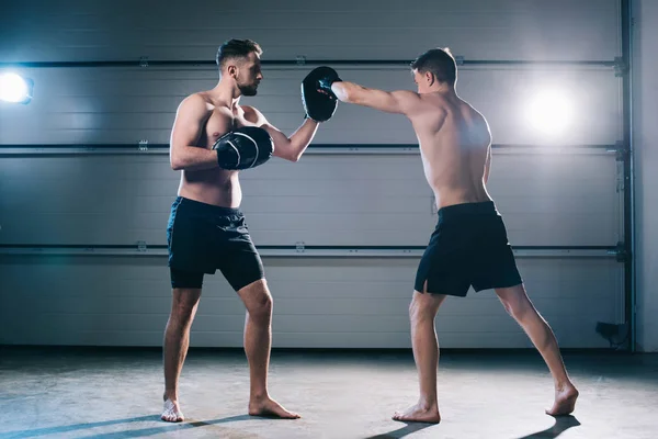运动肌肉不穿的拳击手练习拳打脚踢与另一个运动员在训练中 — 图库照片
