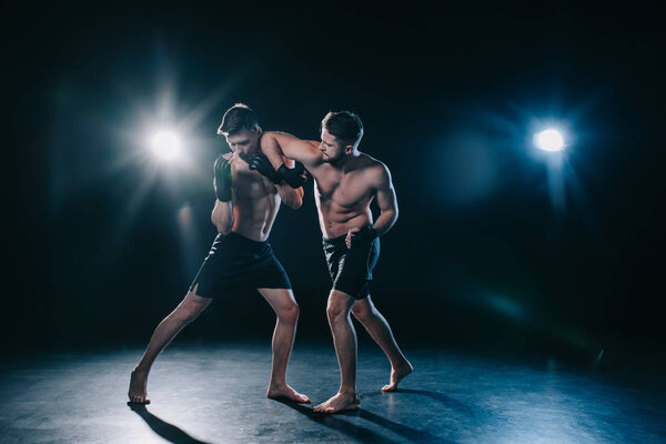 mma fighter punching another sportsman during muay thai training