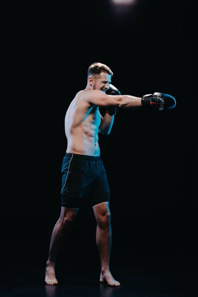 ボクシング グローブ黒に分離されたパンチを行う激しい顔の表情と裸足のスポーティーなボクサー — ストック写真