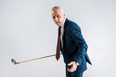 Olgun işadamı oynarken gri izole golf kulübü tutarken odaklı  
