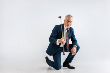 neşeli olgun adam golf club tutan takım elbiseli ve gri otururken
