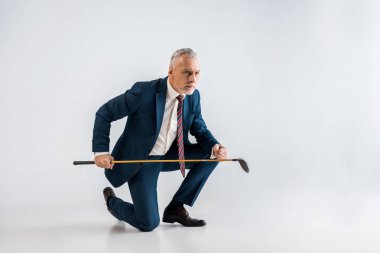 ciddi olgun adam golf club tutan takım elbiseli ve gri otururken