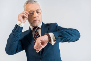 seçici odak gözlük dokunmaktan ve gri izole izle bakarak olgun işadamı