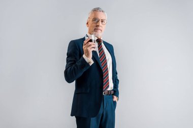 Olgun işadamı gri izole cebinde duran el ile viski cam holding 