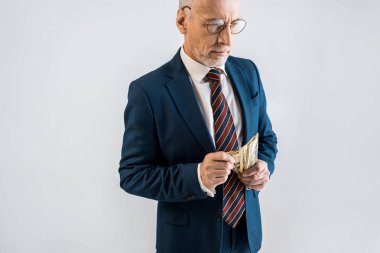 Olgun erkek gözlük ve formal giyim gri izole Doları banknot holding genel gider görünümünü 