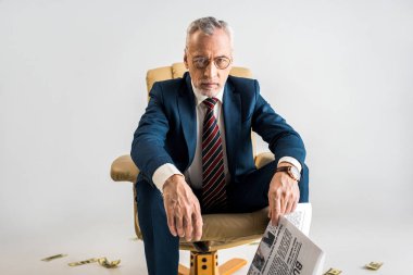 koltuk Doları banknot yakın oturan ve gri izole iş gazete tutan olgun işadamı 