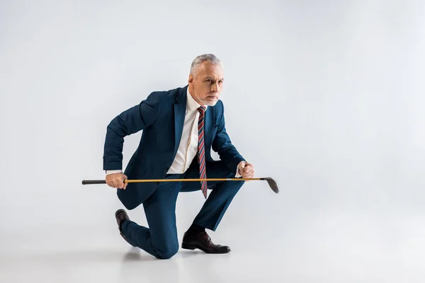 Ernster Reifer Mann Anzug Mit Golfschläger Und Sitzen Auf Grau — Stockfoto