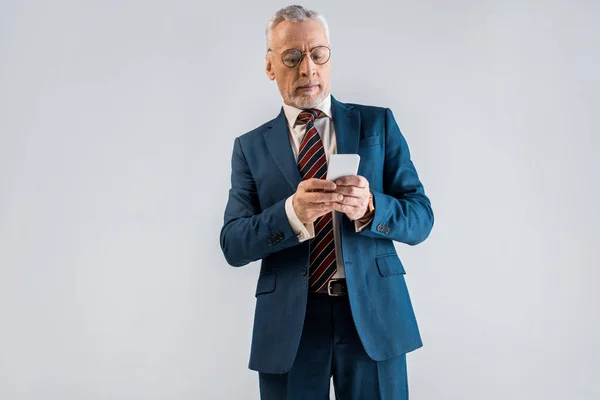 Reifer Geschäftsmann Anzug Blickt Auf Smartphone Isoliert Auf Grau — Stockfoto