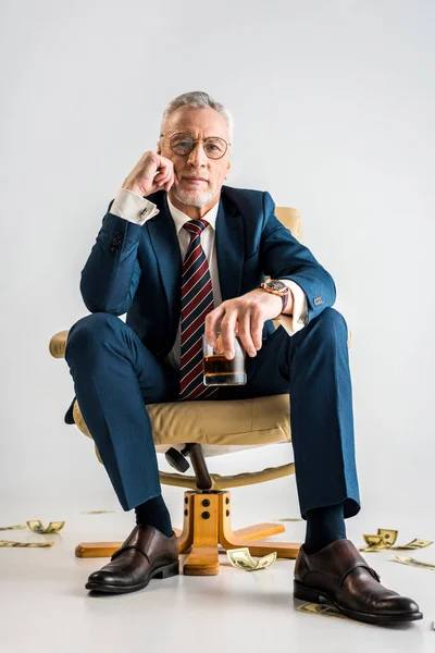 Reifer Geschäftsmann Sitzt Sessel Neben Dollarnoten Und Hält Ein Glas — Stockfoto