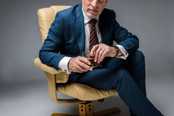 Przycięte Widzenia Dojrzałe Biznesmen Siedząc Fotelu Trzymając Szklankę Whisky Szary — Zdjęcie stockowe
