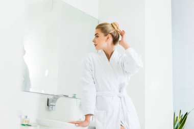 beyaz bornoz banyo aynaya bakarak çekici ve sarışın kadın 