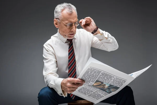 Ώριμες Επιχειρηματία Αγγίζοντας Γυαλιά Διαβάζοντας Εφημερίδα Σχετικά Γκρι — Φωτογραφία Αρχείου