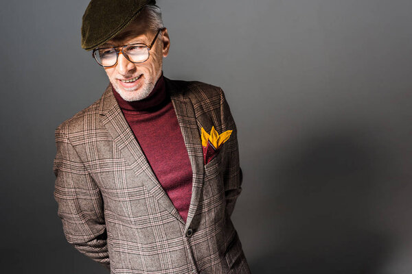 overhead view of happy mature man in cap and glasses standing on grey