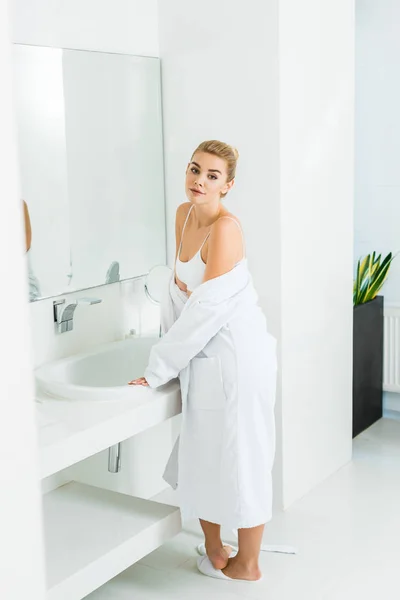 Güzel Sarışın Kadın Banyoda Kamera Bakarak Sutyen Beyaz Bornoz — Stok fotoğraf