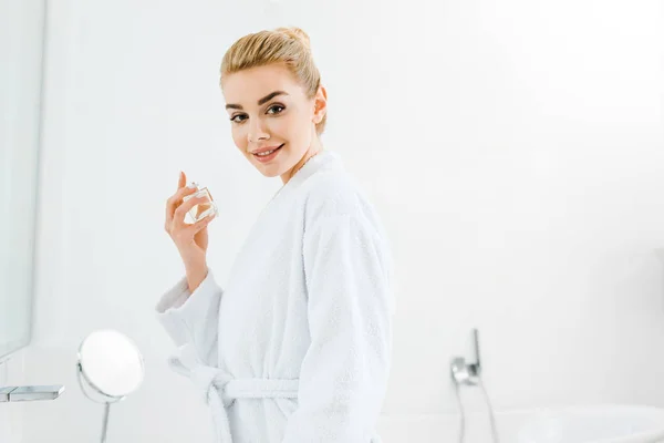 Hermosa Sonriente Mujer Albornoz Celebración Perfume Mirando Cámara — Foto de Stock