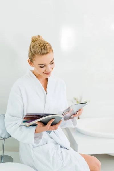Attractive Smiling Woman White Bathrobe Reading Magazine Bathroom — Stock Photo, Image