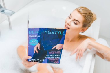 seçici odak köpük ve güzellik ve stil okuma banyoda dergisi banyo çekici ve sarışın kadın 