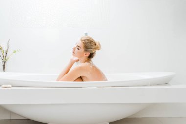 güzel ve sarışın kadın alarak banyo banyo köpüğü ile yan görünüm 