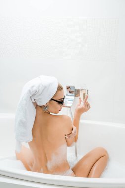arkadan görünüşü güzel kadın beyaz havlu ve banyo ve şampanya kadehi tutan güneş gözlüğü 