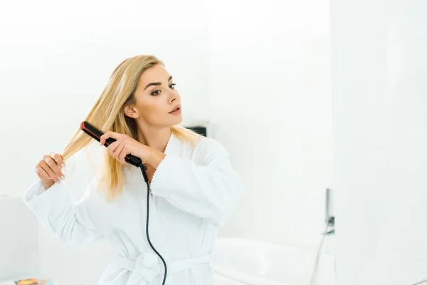 Beautiful Blonde Woman White Bathrobe Using Flat Iron Bathroom — Stock Photo, Image