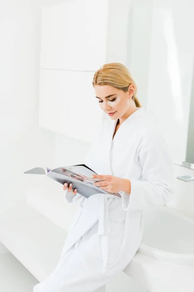 Beautiful Blonde Woman White Bathrobe Eye Patches Face Reading Magazine — Stock Photo, Image