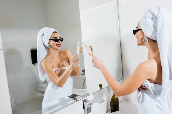 サングラスとシャンパン グラスを押しながら鏡を見てタオルで魅力的で笑顔の女性の選択と集中 — ストック写真