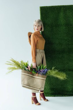güzel şık kız holding çantayla fern ve beyaz ile yeşil çimen çiçekler 