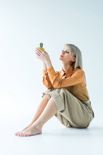 beautiful stylish girl holding cactus plant on white 