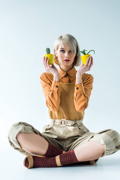 beautiful stylish girl looking at camera and holding flower pots on white 