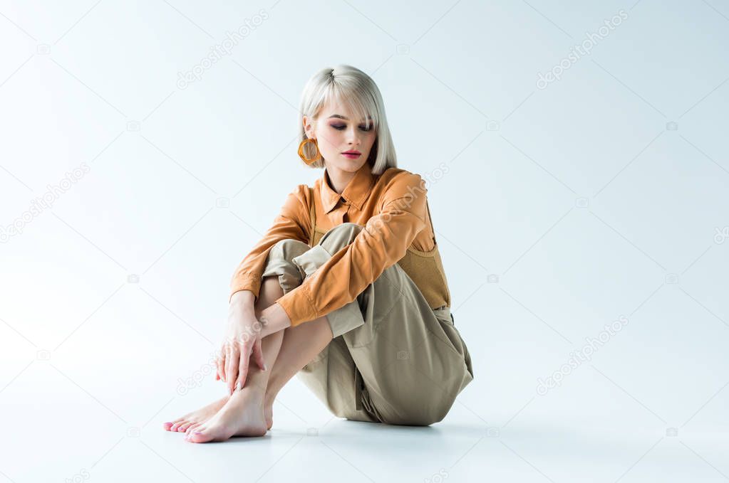beautiful stylish young woman sitting with crossed legs on white 