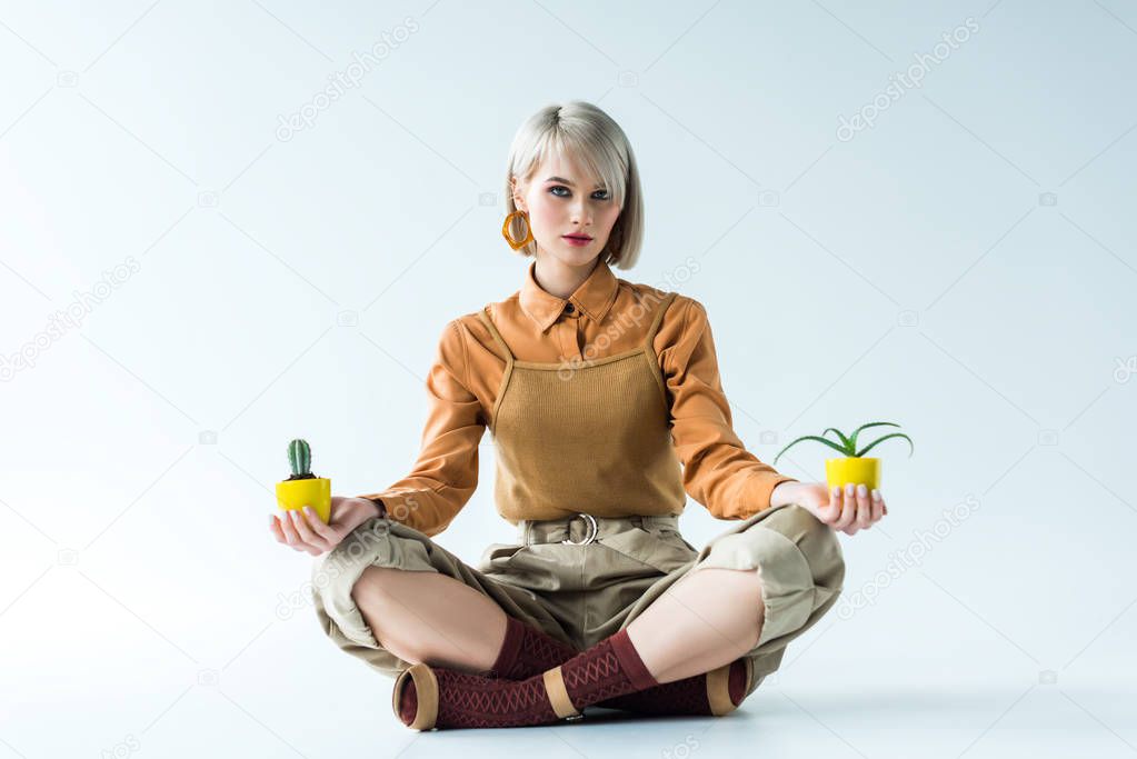 beautiful stylish girl looking at camera and holding flower pots on white