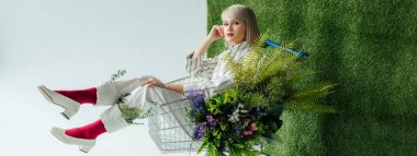 moda kız alışveriş sepeti fern ve yeşil çim beyaz çiçekleri ile oturan panoramik çekim
