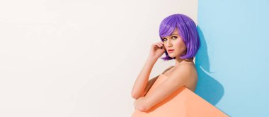 panoramic shot of beautiful girl with purple hair covered in coral paper sheet posing on blue and white with copy space clipart