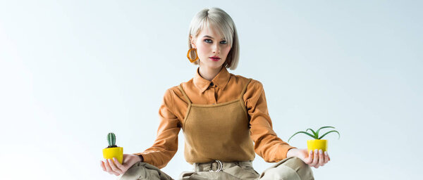 panoramic shot of beautiful stylish girl with flower pots looking at camera isolated on white