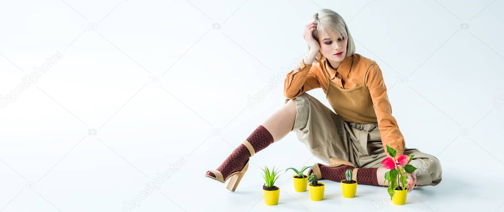 panoramic shot of beautiful stylish girl posing with flower pots isolated on white with copy space
