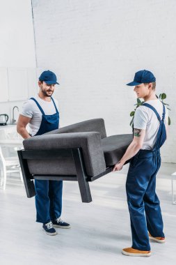 two movers in uniform transporting furniture in apartment clipart