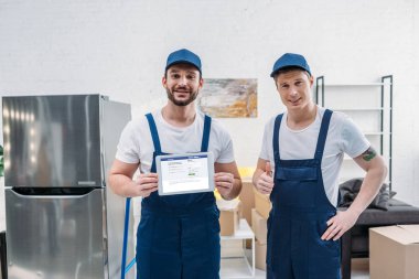 iki Nakliyeciler ekranda Facebook uygulaması ile dijital tablet sunan ve daire yukarı işaret başparmak gösteren