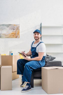 Daire Pano ile karton kutulara yakın otururken üniforma kamera bakarak Mover